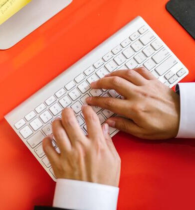 Two hands typing on an apple keyboard.